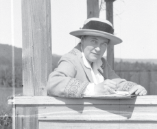 black and white photo of Willa Cather sitting outside while writing 