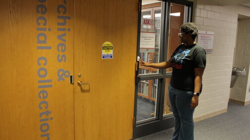 Student ringing the bell outside of the Archives office.