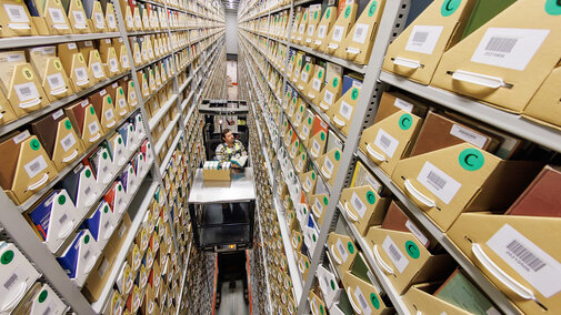 Several stories above the ground, Josh Caster, Archives Manager for University Libraries, retrieves a book stored in the Library Depository Retrieval Facility on East Campus.