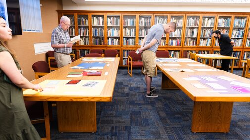 Archival materials on tabletops with people looking at them