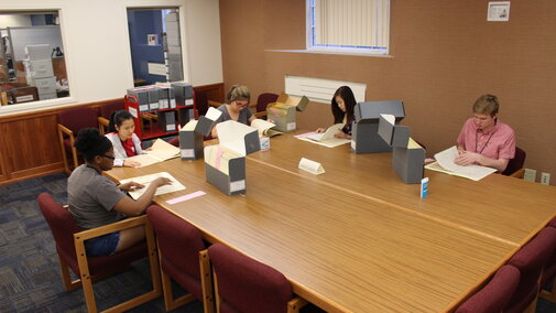 Students sitting at reading room table with archives materials.