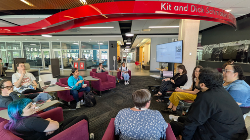 A group of people seated in a circle in a modern lounge area, engaging in discussion.
