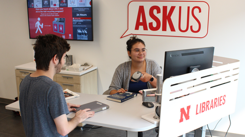 student checking out a book at the askus desk