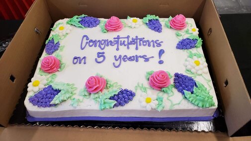 Celebration cake with purple and pink flowers and congratulations on 5 years