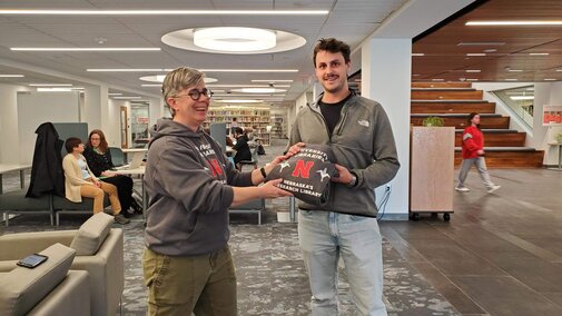 Student receiving Libraries hoodie with Scout Calvert, Research Partnerships Librarian
