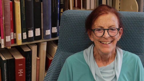 Photo of donor sitting in a chair in the stacks