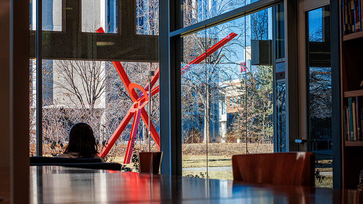 A photo view of the red sculpture, Old Glory, from the vantage of Love Library.