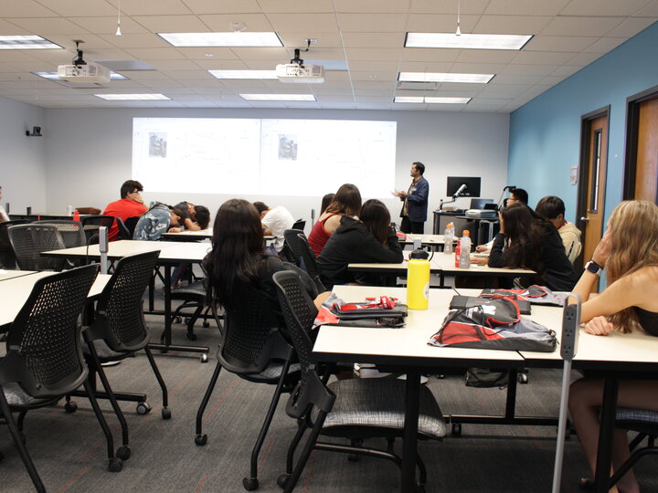 Students sitting at tables watching a presentation