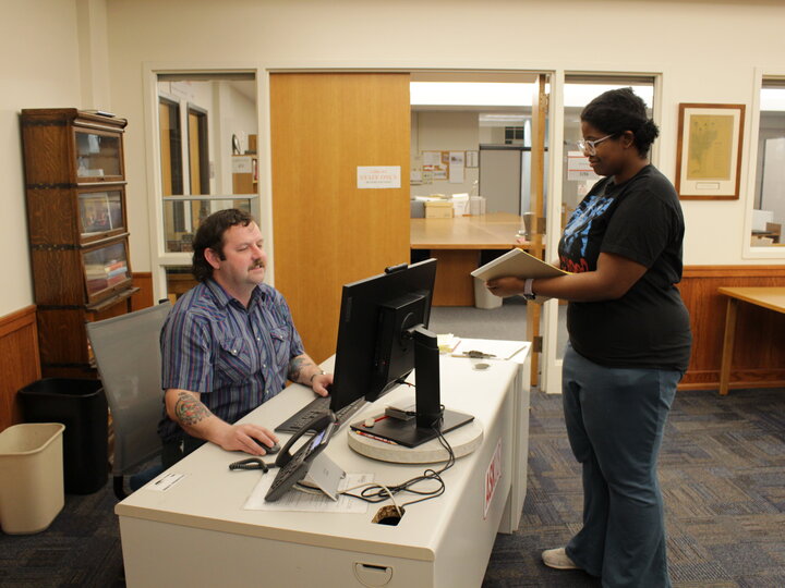 Student getting assistance from an archives staff member at the desk.