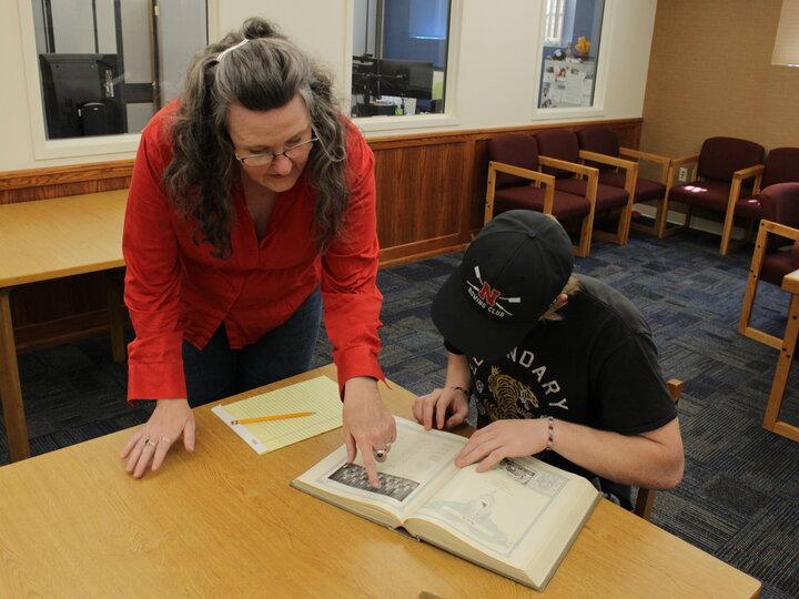 Mary Ellen Ducey assisting a student with materials in the reading room.