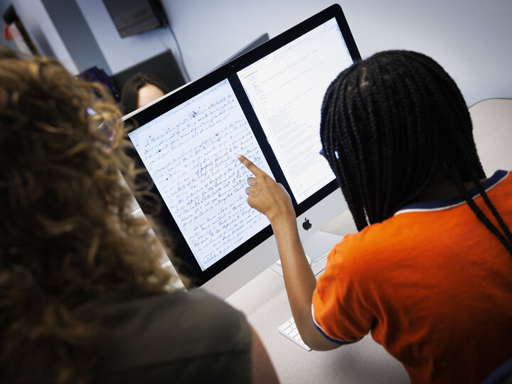 looking over the shoulder of a student pointing to a screen