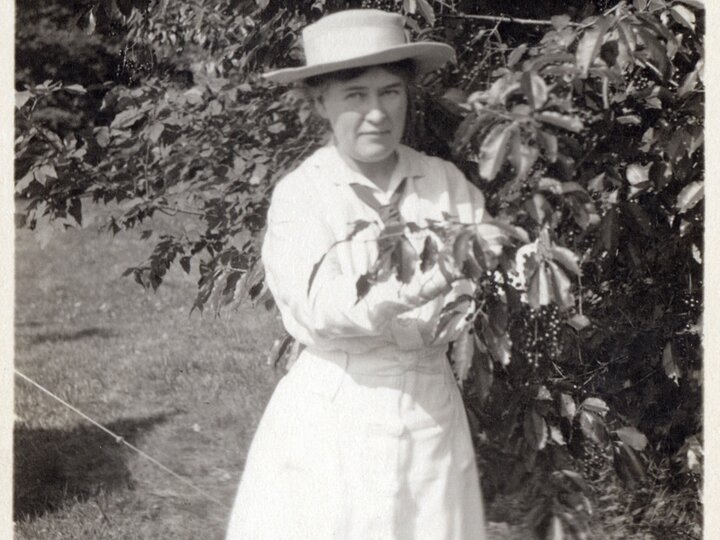 Willa Cather stands next to a tree in the meadow of High Mowing farm near Jaffrey, New Hampshire, where she wrote part of "My Antonia".