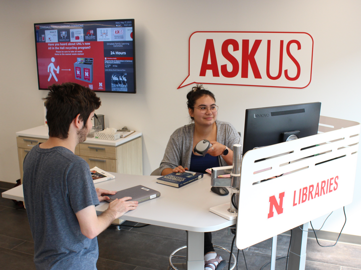 photo of a student checking out a book at the askus desk