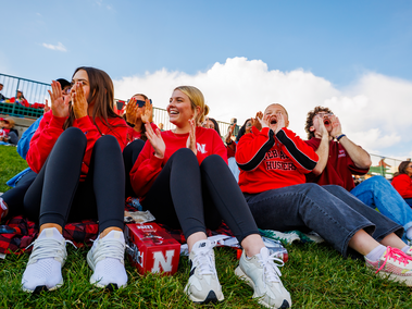 students sitting on a blanket on the lawn cheering and screaming