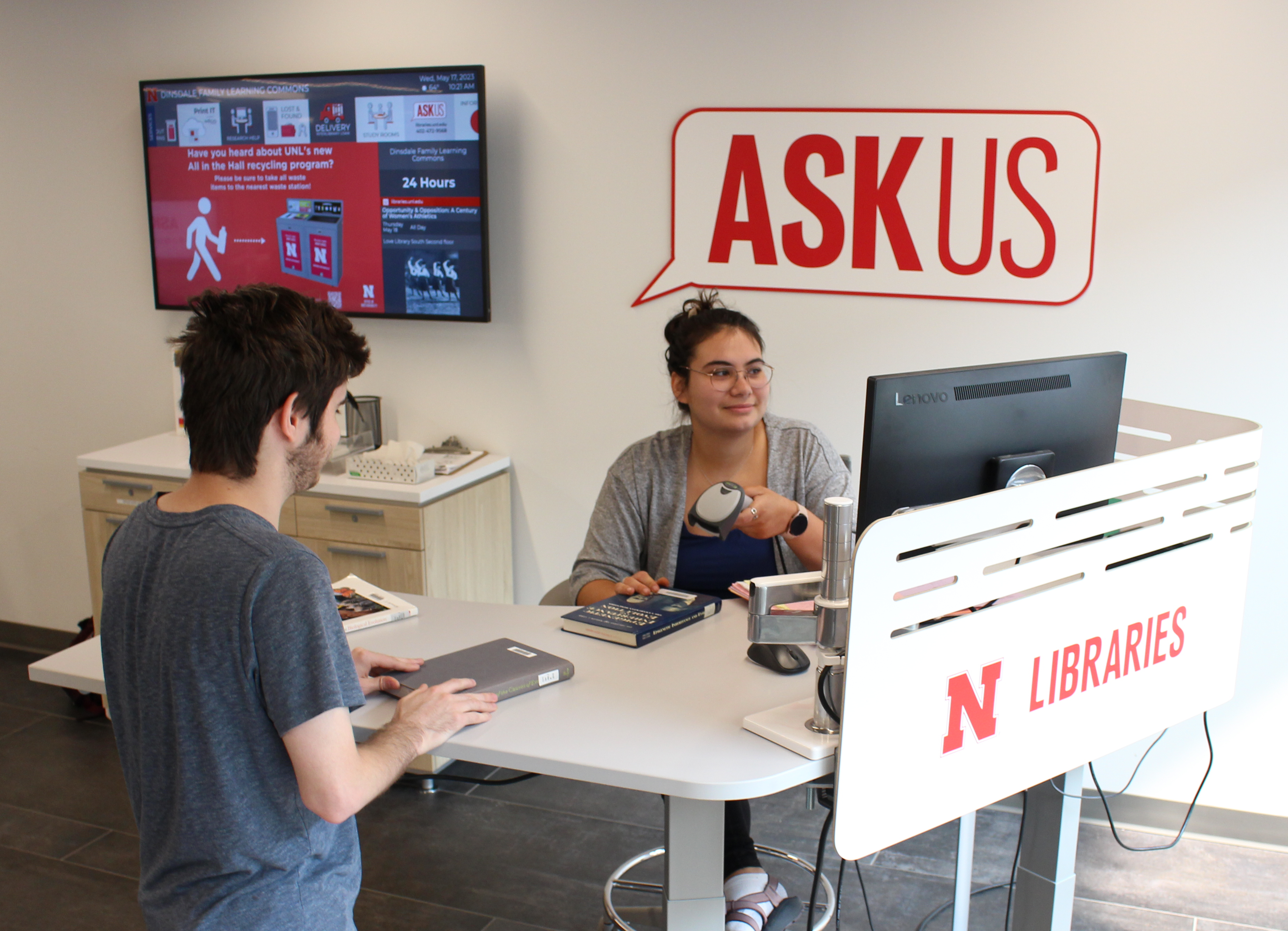 Student checking out a book at an ASKus desk.