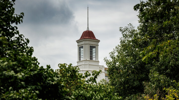 The Love Library cupola is visible through the trees on a cloudy day.