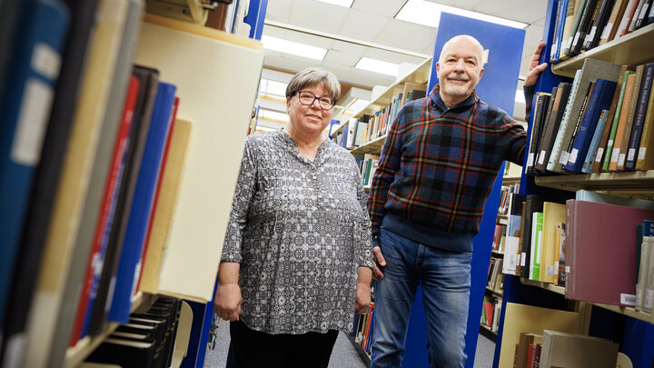 Joanie Barnes (left) and Tom McFarland stand in the stacks of Love Library.