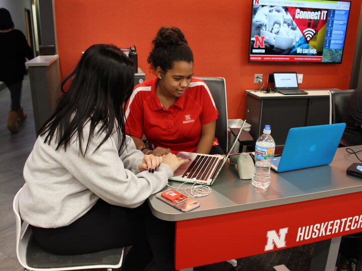 Photo of huskertech employee helping a student with a laptop.