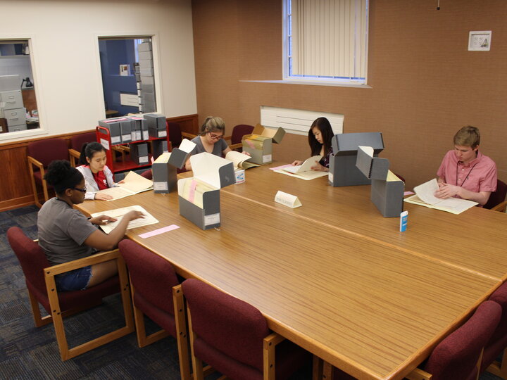 students sitting at table looking at archives materials.