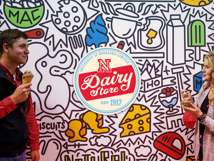 Two people with ice cream in cones standing against a wall with dairy store logo